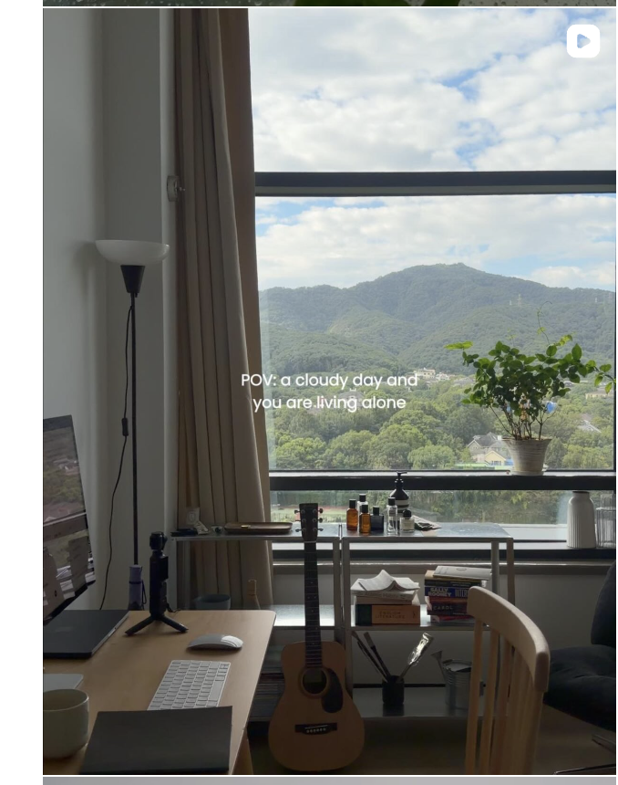 A cloudy mountain view above a desk, guitar and everyday home objects